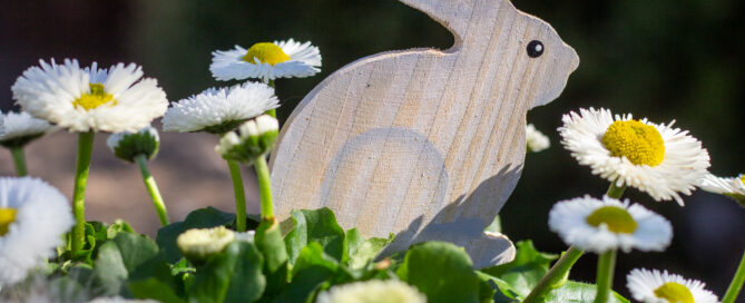Osterhase aus Holz als Dekoration in einem Blumentopf.