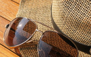 Sonnenbrille liegt auf Sonnenhut.