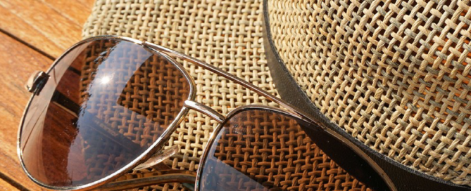 Sonnenbrille liegt auf Sonnenhut.