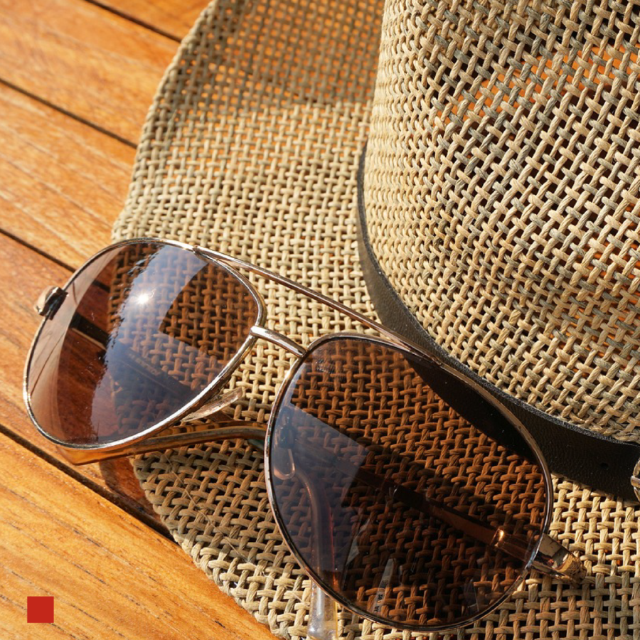 Sonnenbrille liegt auf Sonnenhut.